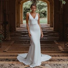 a woman in a white wedding dress standing on the floor with an archway behind her