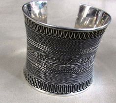 "Sterling silver 2 1/2\" wide cuff bracelet. It looks to be from Bali and is stamped 925 BA. The middle measures 6 1/2\" including the 1 1/8\" opening. The top and bottom are wider. The center row is a flower design. There are several rows of twisted wire and a final row of loops on the top and bottom of the bracelet. The back has on oval of plain silver on each side. The plain silver has some scratches from being worn but is still very pretty and wearable. SBT-3" Silver Engraved Wide Band Bangle, Wide Band Sterling Silver Bracelet, Classic Silver Wide Band Bangle, Wide Cuff Bracelets, Twisted Wire, Wide Cuff, Sterling Silver Bracelet, Tucson, Small Trash Can