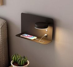 an electronic device is plugged into the side of a wall mounted shelf next to a potted plant