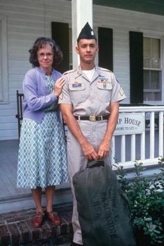 two people standing on the front porch of a house with a bag in their hands