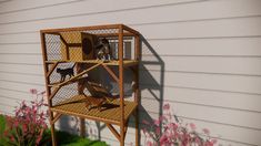 two dogs in a small cage on the side of a house next to pink flowers