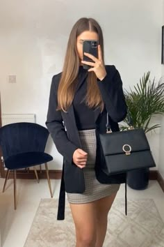 a woman taking a selfie with her cell phone while wearing a skirt and blazer