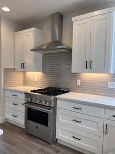 a stove top oven sitting inside of a kitchen next to white cupboards and drawers