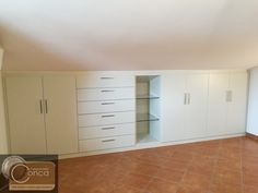 an empty room with white cabinets and tile flooring