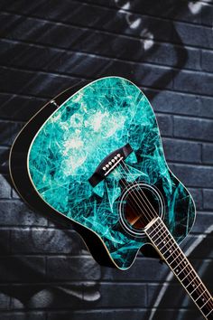 an acoustic guitar sitting against a brick wall