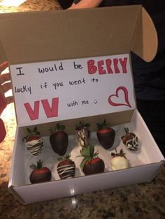 a box filled with chocolate covered strawberries sitting on top of a counter next to a sign