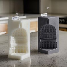 two candles sitting on top of a counter next to each other