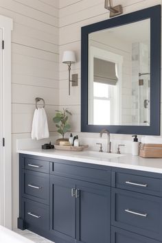 a bathroom with blue cabinets and a large mirror on the wall over the sink area