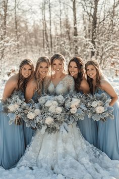 a group of women standing next to each other in the snow holding flowers and bouquets