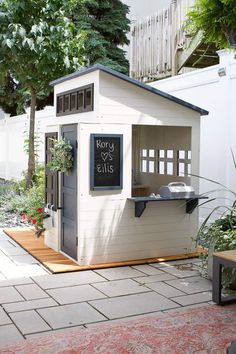 a small white shed with a chalkboard sign on it