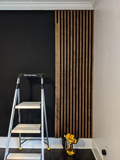 a ladder is next to a black wall with wooden slats