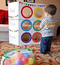 a little boy standing in front of a box filled with balls and playing with his toys