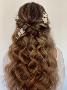 the back of a woman's head with long hair and flowers in her hair