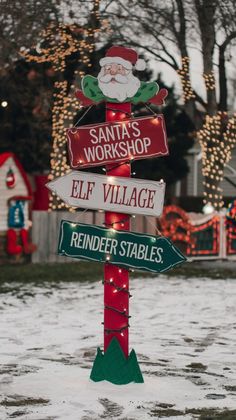 a street sign with santa's workshop, elf village and reindeer stables on it