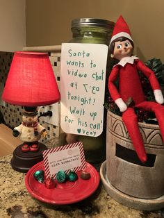 an elf is sitting on top of a potted plant next to a sign that says santa wants to video chat at 7 30 tonight