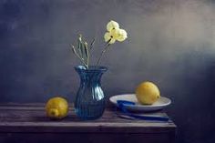 a painting of lemons and flowers in a blue vase on a table with a plate