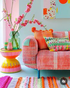 a living room filled with colorful furniture and flowers in vases on the end tables