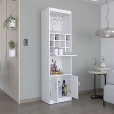 a white cabinet with wine glasses and bottles on it in a living room next to a couch