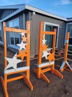 two orange and white wooden chairs sitting in front of a house with stars on them