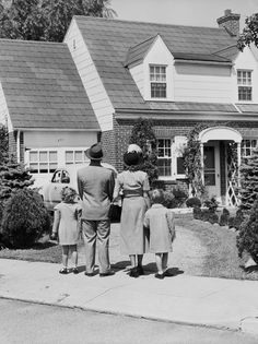 an old black and white photo of three people standing in front of a house