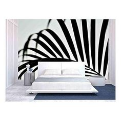 a white bed sitting in front of a black and white wall with an abstract design on it