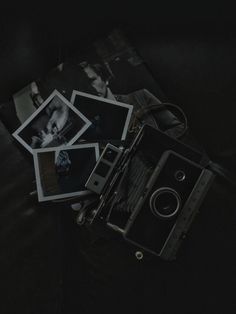 an old camera sitting on top of a black table next to some polaroid pictures