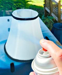 a person is holding a spray bottle in front of a lamp on a blue table