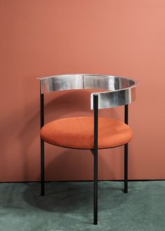 an orange chair sitting in front of a mirror on the floor next to a pink wall