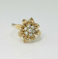 14K Yellow Gold Pearl Flower Ring, 7 round pearls form center of bud tools surrounded by petals in gold buttresed sides, 5/8 inch across, Ring size 9, Circa 1960, 6.4 grams SKU# BB286R07 This listing contains photographs of the actual item you will receive. Our items are in excellent condition with little or no signs of wear and many are one of a kind pre-owned estate finds. Please look closely at the pictures in this listing as they are part of the product description. Please read the descripti Pearl Flower Ring, Gold Coin Ring, Pearl Flower, Fine Jewelry Designers, Blue Topaz Ring, Multi Stone Ring, Gold Coins, Flower Ring, Multi Stone