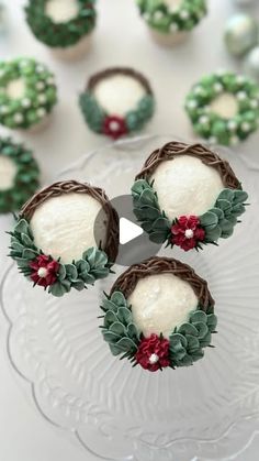 cupcakes decorated with green and red decorations on a glass platter next to other cupcakes