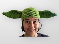 a woman wearing a crocheted yoda hat