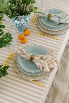 the table is set with blue and white plates, napkins, and oranges