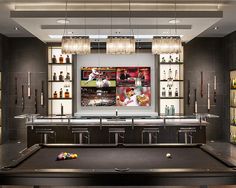 a pool table in the middle of a room with liquor bottles on shelves behind it