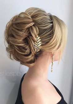 a woman with blonde hair in a low updo and gold leaves on her head