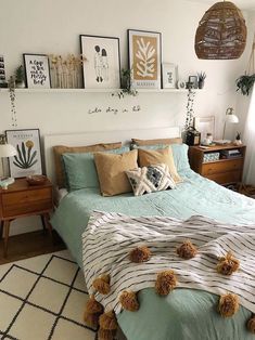 a bed room with a neatly made bed and lots of pictures on the wall above it