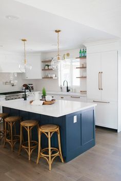 a kitchen with an island and stools in the center, along with white cabinets