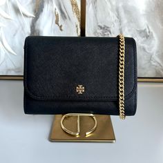 Like New Tory Burch Emerson Chain Wallet Shoulder Leather Crossbody Bag Color: Black Detachable Chain Crossbody Strap Magnetic Snap Closure Two Interior Slip Pockets 6 Interior Card Slots Interior Zip Pocket Exterior Slip Pocket Tb Logo Plaque On Front Strap Drop : 23" Dimensions: W: 7.5" D: 2" H: 5" High- Quality Scratch- Resistant Saffiano Leather 100 % Authentic Tory Burch Tory Burch Britten Crossbody Bag, Tory Burch Emerson, Black Crossbody Bag Tory Burch, Tory Burch Crossbody Bag, Tory Burch Clutch, Black Wallet With Gold-tone Hardware Crossbody, Chain Wallet, Tory Burch Bag, Wallet Chain