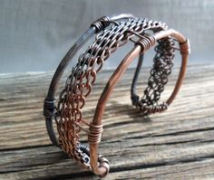 Woven ~  Art imitating lifes interweaving journeys of ups and downs. My depiction is brought to life by using complex metal weaving, colors altered through heating techniques and hammering.   A carefully woven band created from 5 copper wires was placed in the center of a 10 gauge hammered wire frame. I then oxidized one side of the cuff with my gunsmoke patina and polished to a dull shine. I applied a non-yellowing jewelers lacquer to maintain the patina and to discourage against skin discoloration. This cuff bracelet is 6 inches long and 1 inch wide. Handmade Artisan Metal Cuff Bracelet, Artisan Metal Cuff Bangle Bracelet, Handmade Metal Fusion Cuff Bracelet, Handmade Fusion Metal Cuff Bracelet, Handmade Fusion Style Metal Cuff Bracelet, Rustic Handmade Cuff Bangle Bracelet, Artisan Hand Forged Adjustable Cuff Bracelet, Silver Artisan Cuff Bracelet In Copper, Artisan Cuff Bracelet With Unique Variations