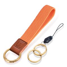 an orange belt with two gold rings and a caramel colored lanyard on a white background