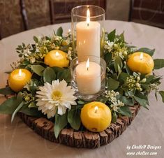 a table topped with candles and lemons on top of a wooden tray filled with greenery