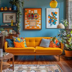 a living room with blue walls and yellow couches, potted plants and pictures on the wall