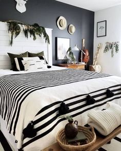 a bed with black and white striped bedspread in a bedroom next to plants