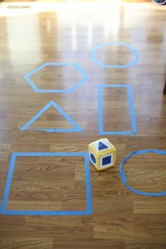 a wooden floor with blue tape on it and a yellow cube sitting in the middle