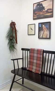 a wooden bench sitting next to a wall with pictures hanging on it's side