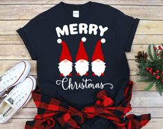 a black shirt with red and white christmas gnomes on it next to some pine branches