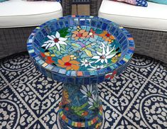 a glass table sitting on top of a rug next to two white chairs and pillows