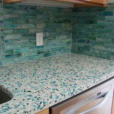 a kitchen with a sink, dishwasher and tiled backsplash in it