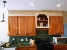 a kitchen with wooden cabinets and green tile backsplash, black stove top oven and microwave