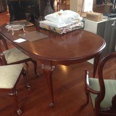 a wooden table with chairs around it in a room filled with furniture and other items