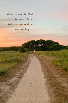 two people walking down a dirt road in the middle of a field